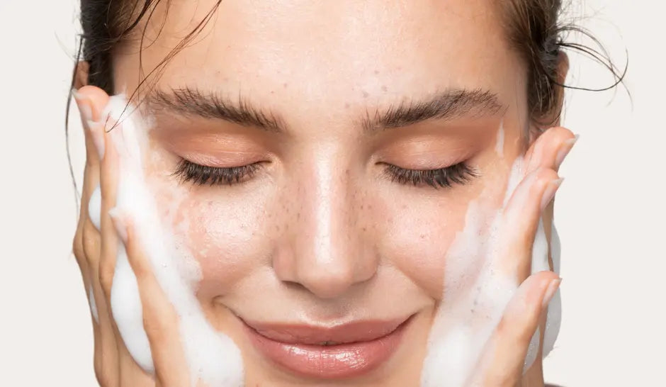 femme qui met de la mousse cadellia nettoyante sur le visage